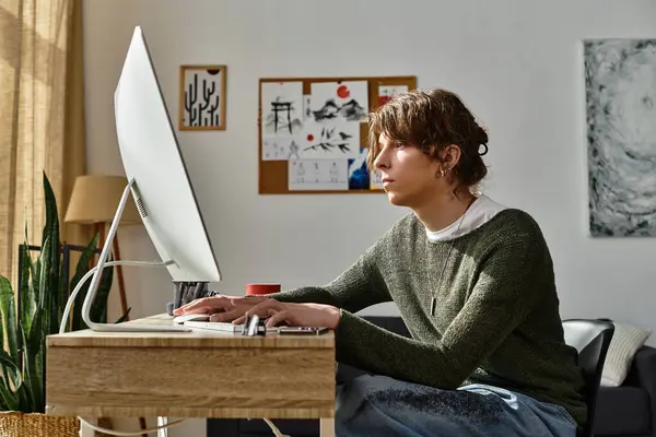 A young man studies attentively at a desk with a computer in a bright space. — Stock Photo