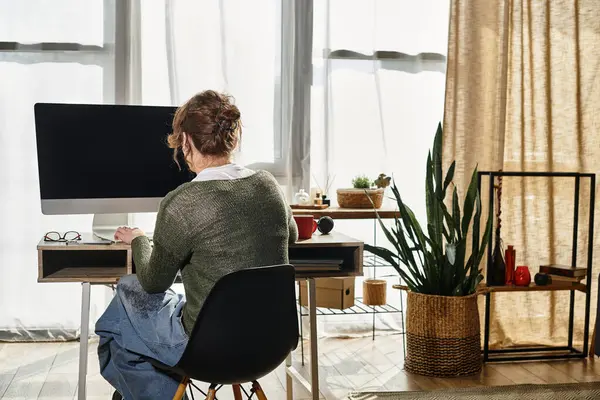 Ein engagierter junger Student vertieft sich zu Hause in akademische Arbeit, umgeben von Pflanzen und Sonnenlicht. — Stockfoto