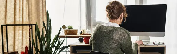 A dedicated young man studies intently at home, surrounded by plants and natural light. — Stock Photo