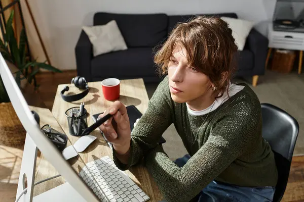 Estudiante joven enfocado que trabaja desde casa, utilizando la tecnología y la creatividad para estudiar con eficacia. - foto de stock
