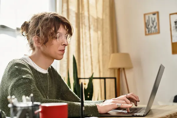Ein junger Student konzentriert sich auf seinen Laptop und vertieft sich von zu Hause aus in das Studium. — Stockfoto