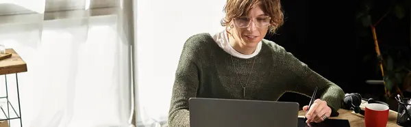 Junger Mann studiert zu Hause mit Laptop, umgeben von Notizen und einer warmen Atmosphäre. — Stockfoto