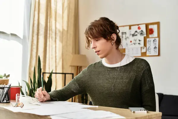 Un giovane concentrato studia e disegna alla scrivania di casa, circondato da appunti e piante. — Foto stock