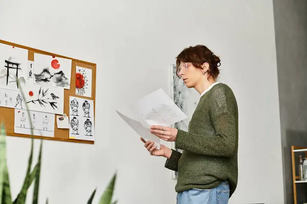 In a cozy home environment, a dedicated young student studies sketches with attention to detail. — Stock Photo