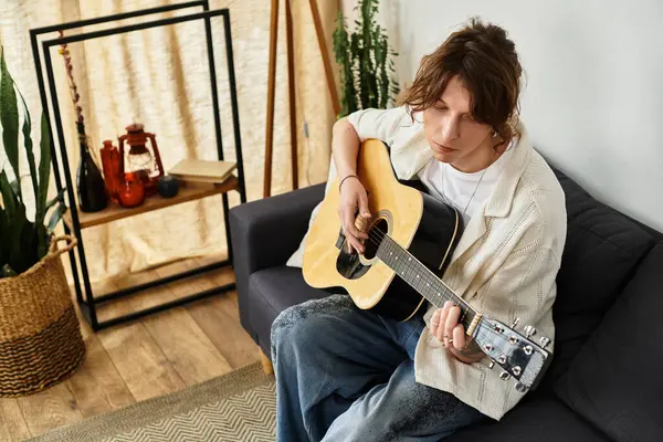 A young student enjoys strumming his guitar in a calm and inviting home environment. — Stock Photo