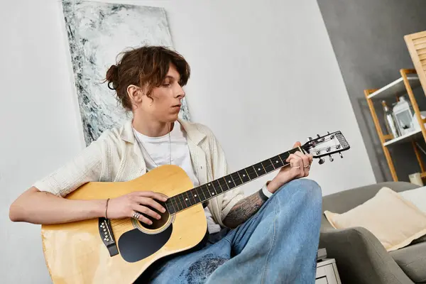 A young student engages in music by strumming a guitar, immersed in creativity and comfort. — Stock Photo