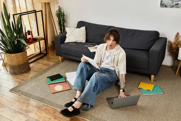 A young man studies at home, surrounded by textbooks and a laptop in a productive setting. — Stock Photo