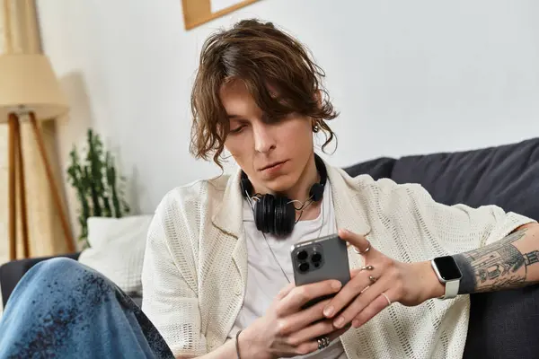 Junger Mann studiert zu Hause, benutzt sein Handy und hört über Kopfhörer zu. — Stockfoto