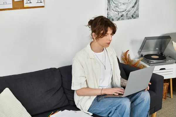 Um jovem focado estuda em seu laptop a partir do conforto de sua casa, enquanto cercado por decoração. — Fotografia de Stock