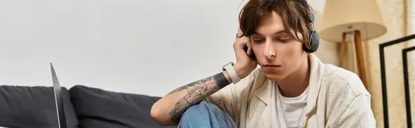 Junger Mann studiert intensiv zu Hause, trägt Kopfhörer, umgeben von einer gemütlichen Umgebung — Stockfoto