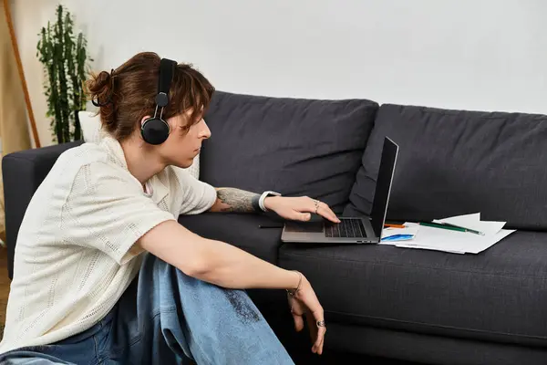 Jovem focado se envolve em estudar em casa com fones de ouvido e materiais escolares nas proximidades. — Fotografia de Stock