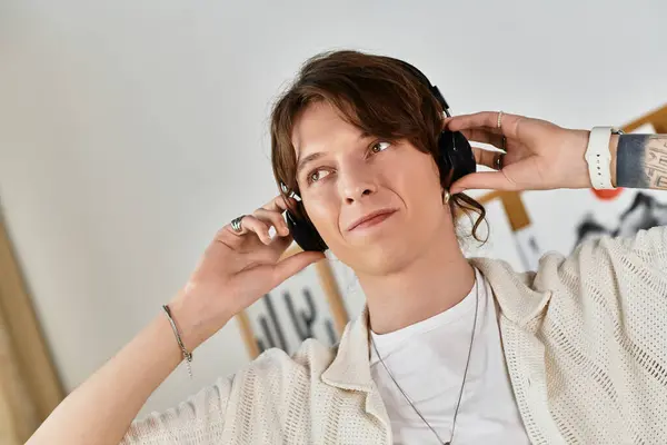 Un giovane uomo ascolta la musica attraverso le cuffie, immerso nei suoi studi in un ambiente domestico accogliente. — Foto stock