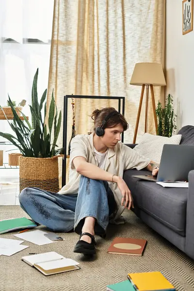 Young student sits on the floor with headphones on, engaged in online classes at home. — Stock Photo