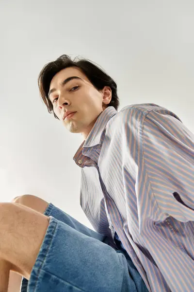 Stilvolle junge nicht binäre Person sitzt selbstbewusst und präsentiert lebendige Mode und Identität. — Stockfoto