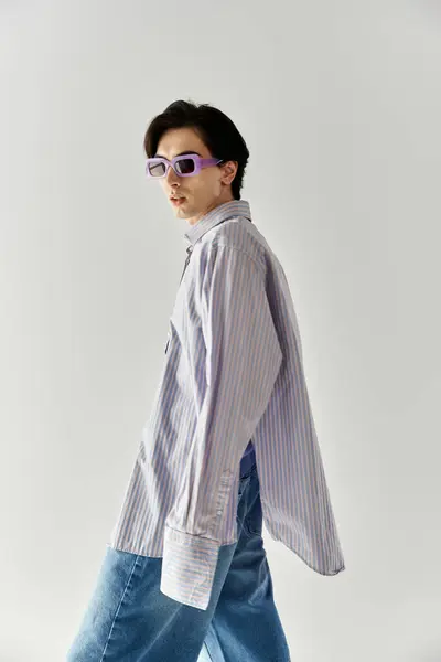 Stylish young non binary person showcases confidence in vibrant attire against a simple backdrop. — Stock Photo