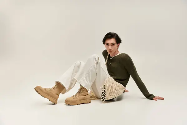 Giovane individuo non binario mette in mostra unico stile di moda, mentre seduto elegantemente in uno studio. — Foto stock