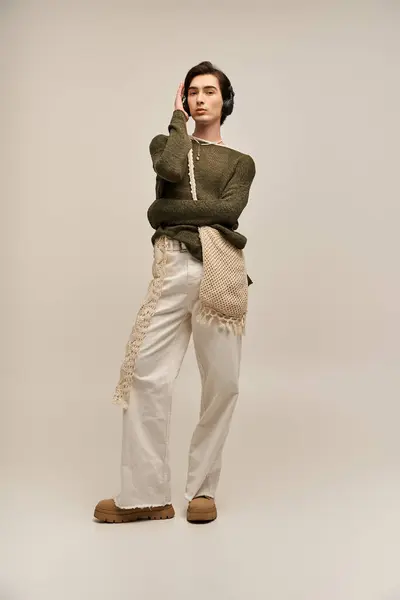 A young non binary person with a stylish outfit poses thoughtfully in a light-filled studio. — Stock Photo