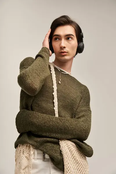 A stylish young non binary individual showcases their unique fashion sense while listening to music. — Stock Photo