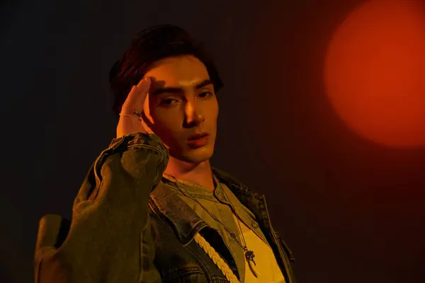 A young, fashionable non binary individual poses confidently with a striking backdrop at dusk. — Stock Photo