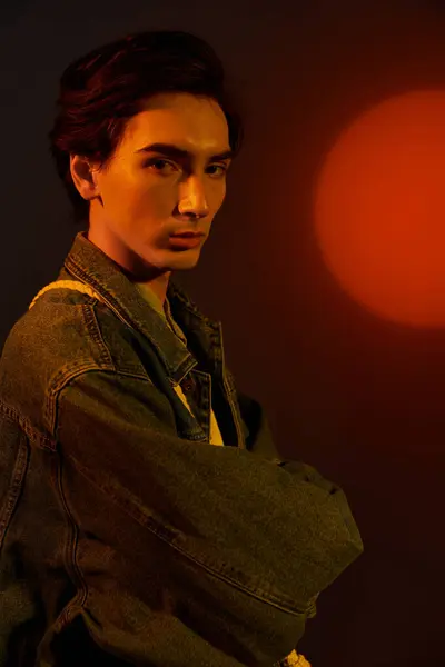 Une jeune personne élégante non binaire pose en toute confiance contre un coucher de soleil vibrant de manière unique. — Photo de stock