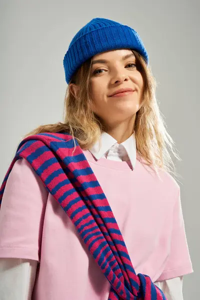 A young woman poses in a trendy outfit and blue beanie in a studio. — Stock Photo