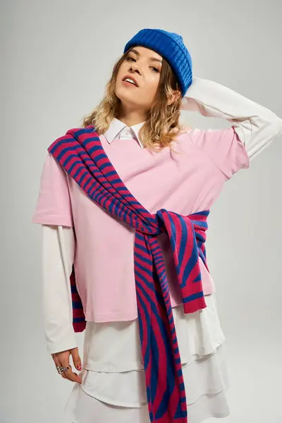 Una bella giovane donna mostra il suo vestito alla moda con un berretto blu in uno studio moderno. — Foto stock