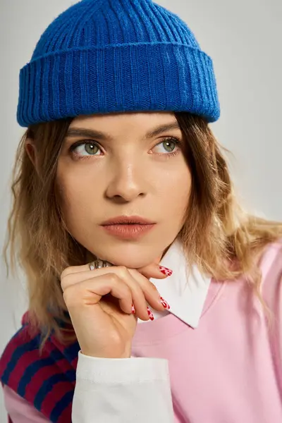 A stylish young woman poses gracefully in a bright studio, showcasing her beanie. — Stock Photo