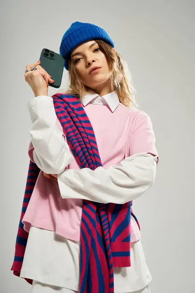 Una giovane donna mette in mostra il suo vestito alla moda mentre tiene in mano uno smartphone in un ambiente di studio chic. — Foto stock