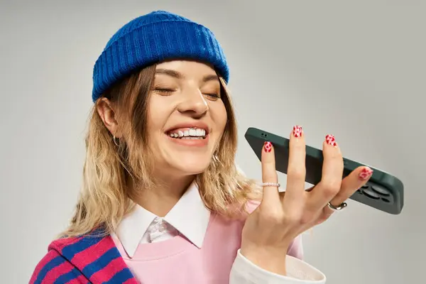 Diese stylische junge Frau genießt einen Moment mit ihrem Handy und strahlt Glück in einem kreativen Atelier aus. — Stockfoto