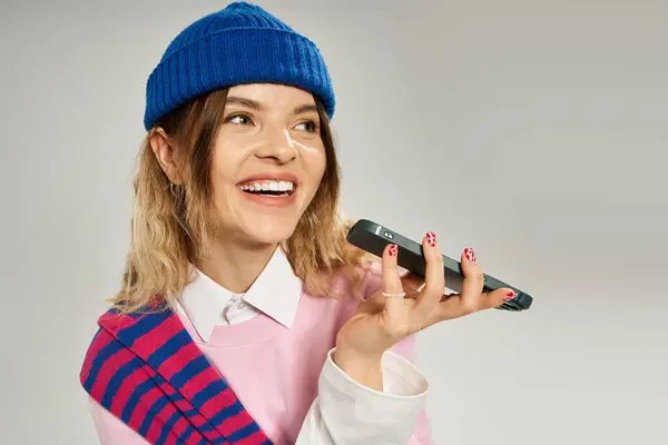 Mulher bonita com um gorro azul ri enquanto fala em seu telefone, irradiando alegria. — Fotografia de Stock