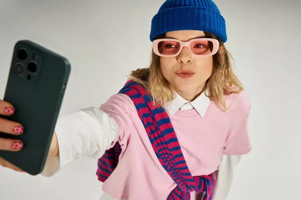 Una mujer joven posa con confianza, mostrando su atuendo de moda y accesorios coloridos en un estudio. - foto de stock