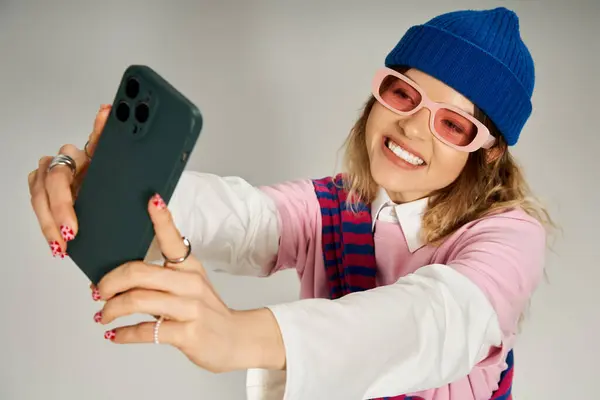 Bright studio showcases a young woman dressed in a playful outfit enjoying a selfie moment. — Stock Photo