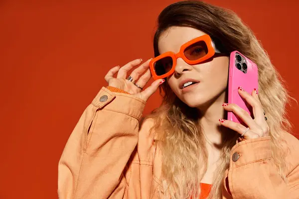 Charming young woman poses confidently in trendy ensemble while holding a smartphone, exuding flair. — Stock Photo