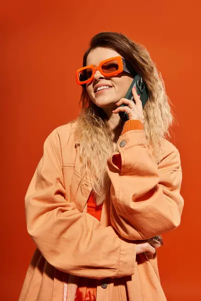 Eine junge Frau genießt einen Moment, während sie in einem stylischen Outfit mit ihrem Handy plaudert. — Stockfoto