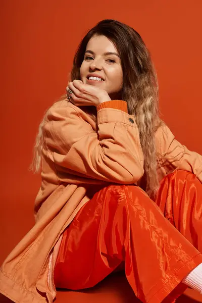 Una mujer joven disfruta de un momento lúdico, vestida con un traje colorido con una sonrisa alegre. - foto de stock