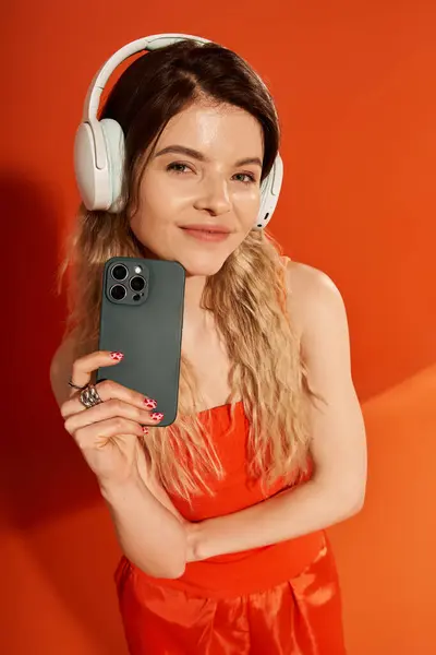 A young woman confidently poses in a vibrant outfit with headphones and a smartphone. — Stock Photo