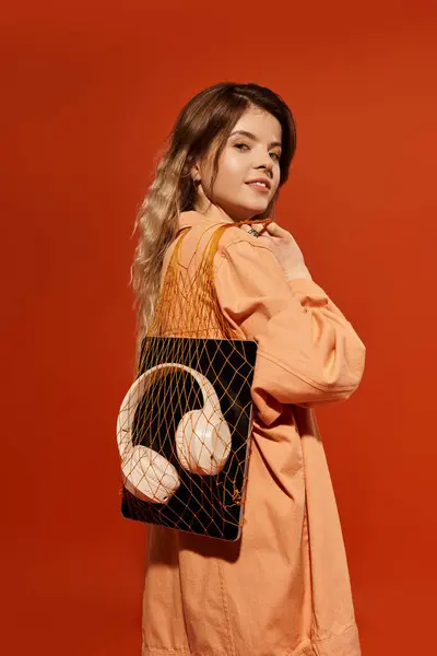 A young woman confidently poses in a stylish outfit against an orange backdrop. — Stock Photo