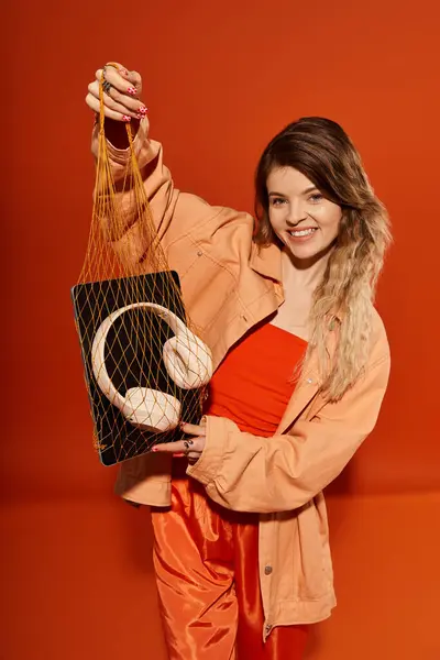 Brightly dressed young woman showcases trendy outfit while holding a stylish accessory bag. — Stock Photo