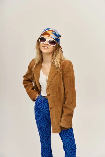 A young woman confidently poses in a trendy outfit against a soft grey backdrop. — Stock Photo