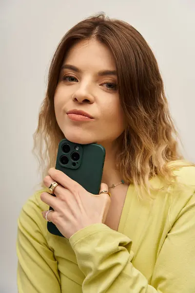 Young woman showcases her fashionable outfit while holding her phone with poise and charm. — Stock Photo