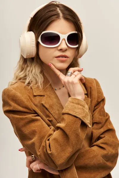 Una hermosa joven emana confianza en un atuendo moderno mientras posa pensativamente contra el gris. - foto de stock