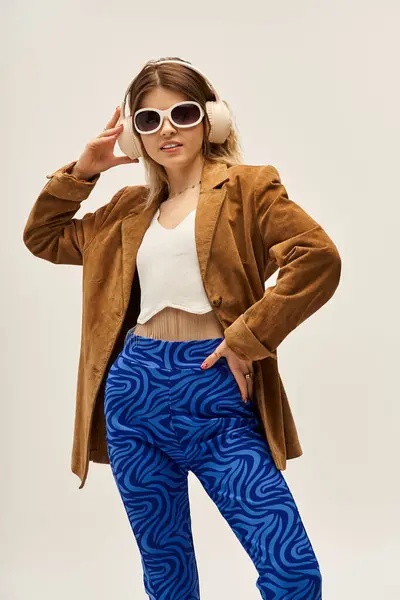 A stylish young woman displays her chic outfit against a soft grey backdrop, exuding confidence. — Stock Photo