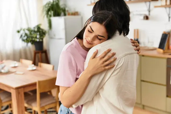 A couple shares a tender moment in their cozy kitchen, embracing warmly. — Stock Photo