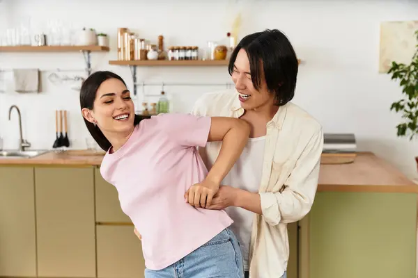 Zwei glückliche Menschen genießen gemeinsam verspielte Momente bei der Zubereitung einer Mahlzeit in ihrer einladenden Küche. — Stockfoto