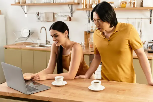 Um casal compartilha um momento acolhedor em sua cozinha, desfrutando de café e um laptop juntos. — Fotografia de Stock