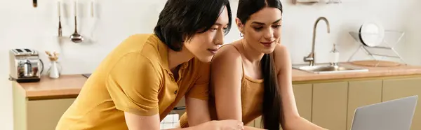 A couple approaches their laptop with smiles, enjoying a shared moment in their stylish kitchen. — Stock Photo