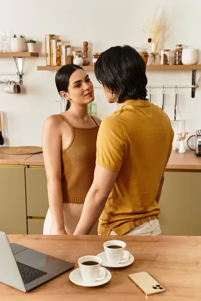 Ein Paar umarmt sich sanft in seiner gemütlichen Küche und teilt intimes Lachen über Tassen Kaffee. — Stockfoto
