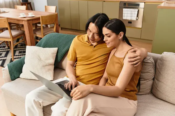 Um casal compartilha um momento quente como eles usam um laptop juntos em sua acolhedora sala de estar. — Fotografia de Stock