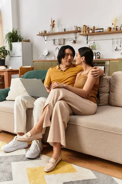 A couple snuggles together on a sofa, immersed in a tender moment at their home, smiles glow. — Stock Photo