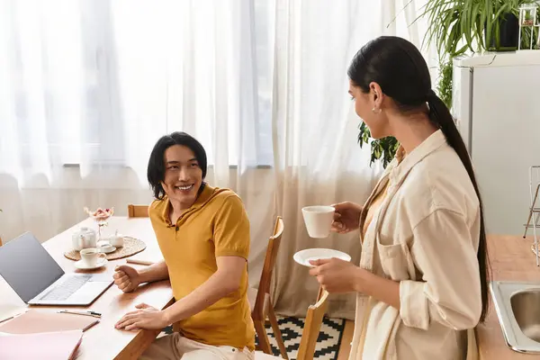 A loving couple shares smiles over coffee in their sunlit kitchen during the morning. — Stock Photo